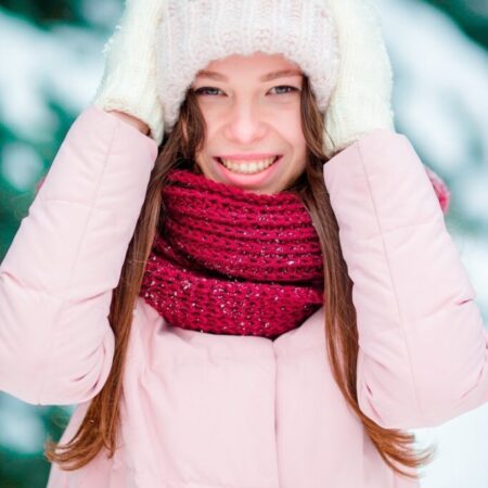 Portrait of beautiful girl smiling outdoors on beautiful winter snow day