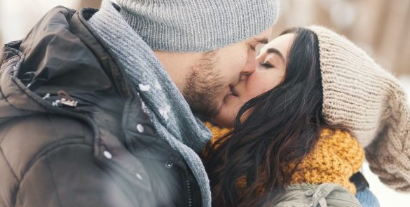 A happy young man and woman kissing in winter enjoying life and