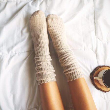 Soft photo of woman on the bed with cup of coffee, top view